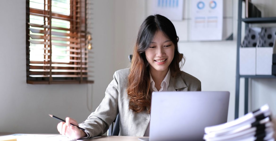 young smiling Asian businesswoman working on laptop. Asia businesswoman working document finance