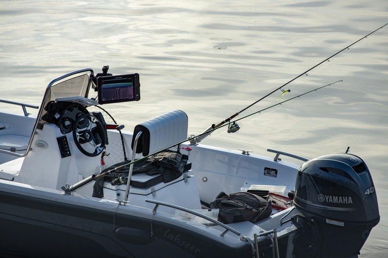 A center console boat equipped with a dive ladder and spearfishing gear, anchored in clear blue water.
