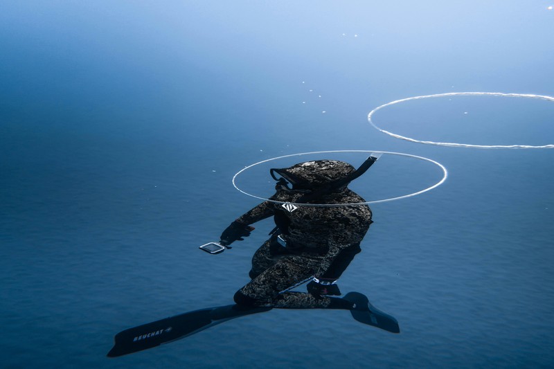 Diver test firing a speargun in clear shallow water